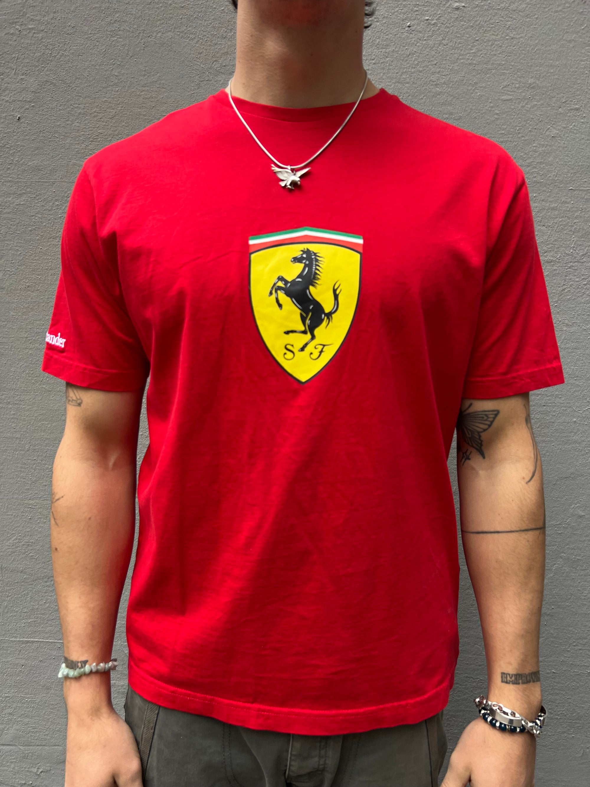 Zu sehnest ein roter Ferrari Tshirt mit dem Logo I der Mitte der Brust 