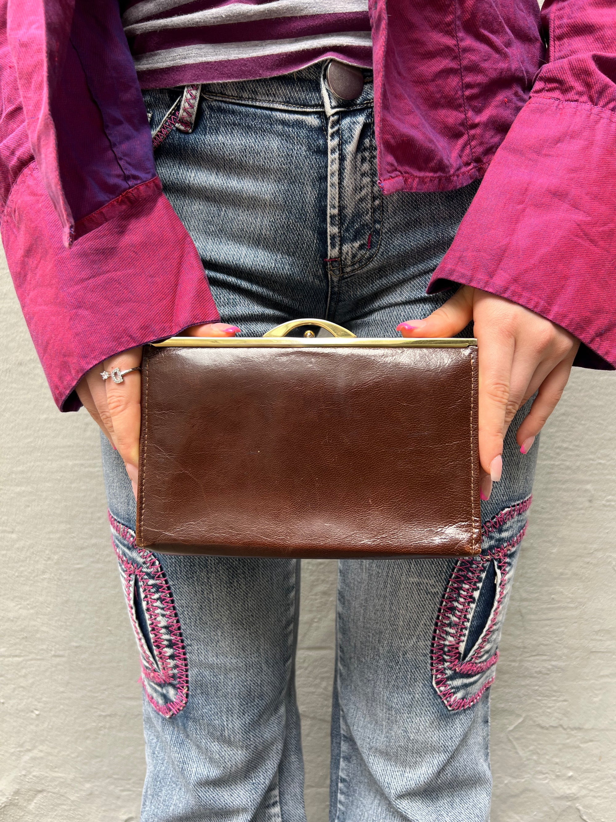 Zu sehen ist eine braune Vintage Leder Tasche getragen vor einem grauen Hintergrund