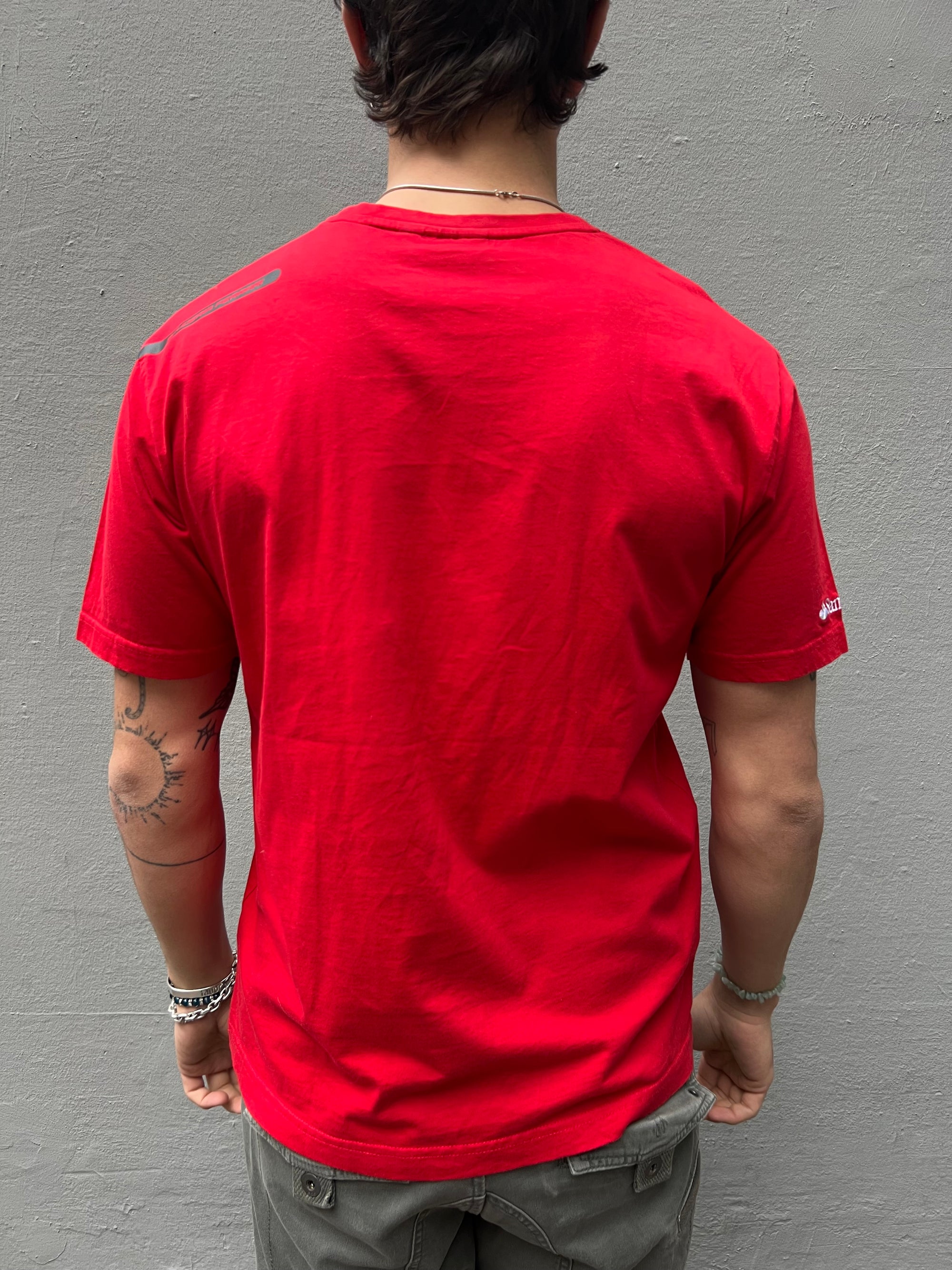 Zu sehnest ein roter Ferrari Tshirt mit dem Logo I der Mitte der Brust 