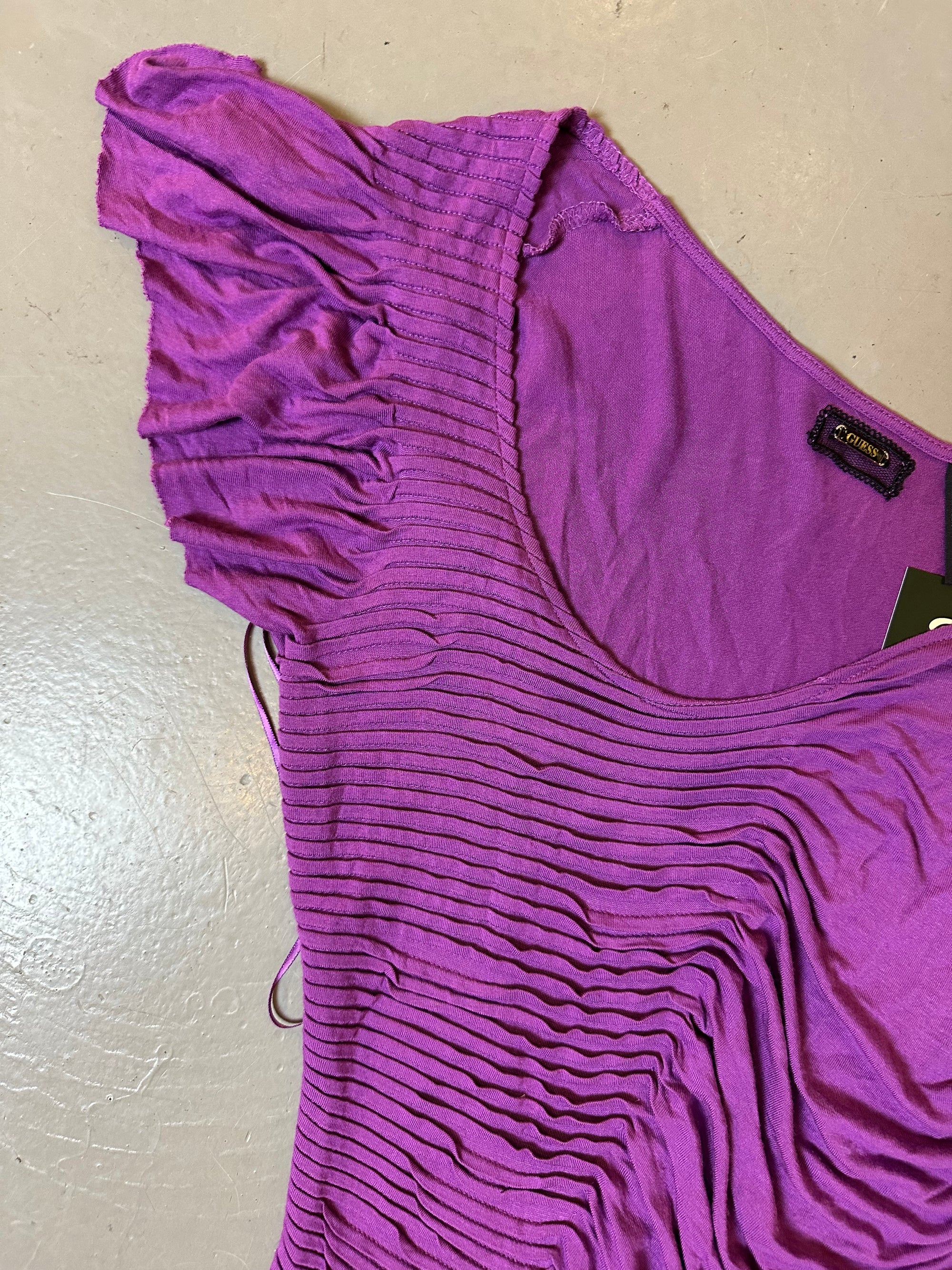 Zu sehen ist ein Lila Mini Kleid/Top von Guess mit unsymmetrischen Ärmeln und Riffelung.