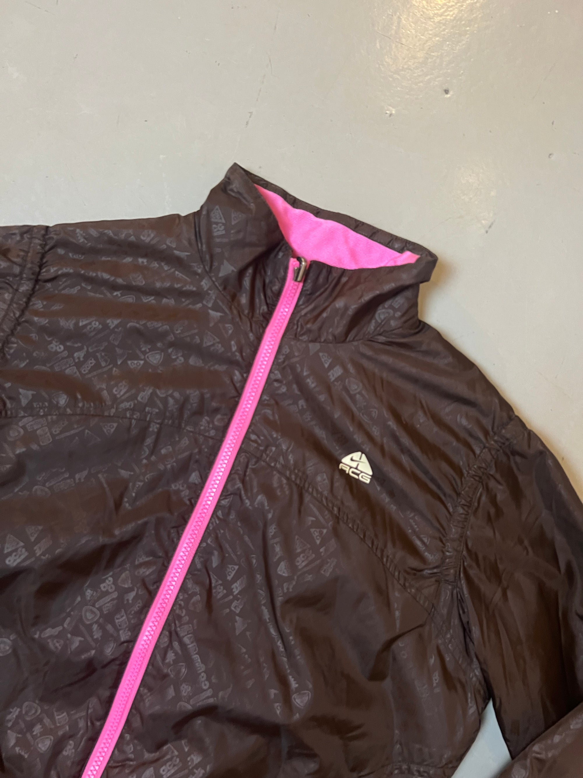 Zu sehen ist eine braune Nike ACG Jacke mit pinkem Reißverschluss 