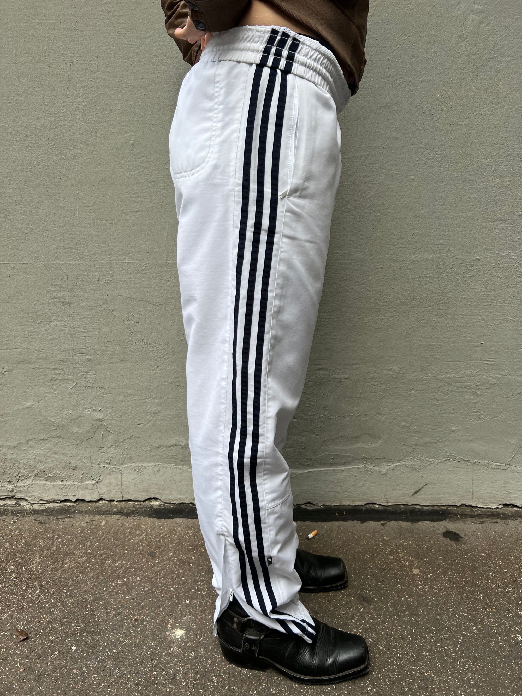 Zu sehen ist eine weiße Adidas Trackpants mit schwarzen Streifen an der Seite 