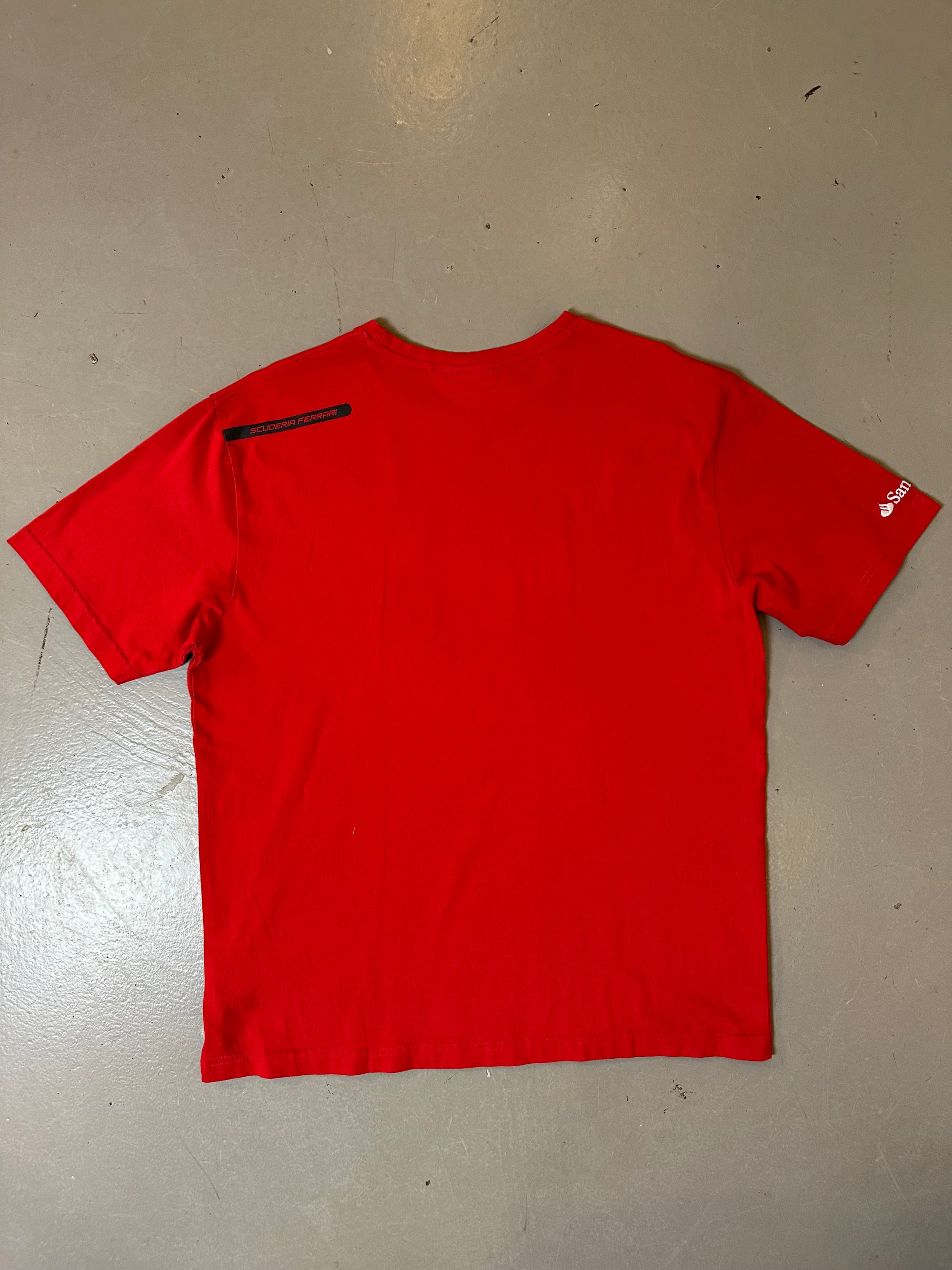 Zu sehnest ein roter Ferrari Tshirt mit dem Logo I der Mitte der Brust 