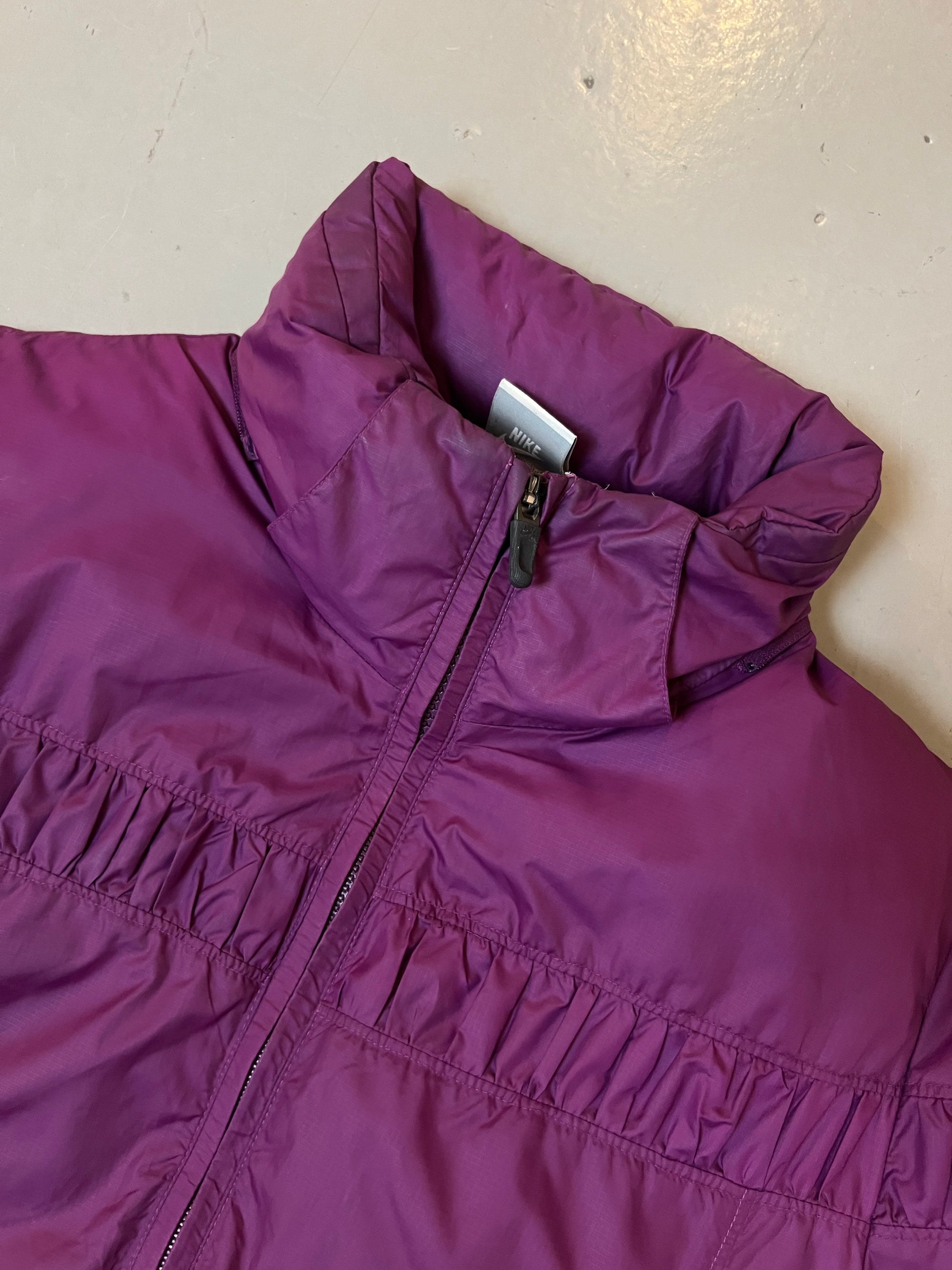 Zu sehen ist eine schlichte lila Winterjacke von Nike