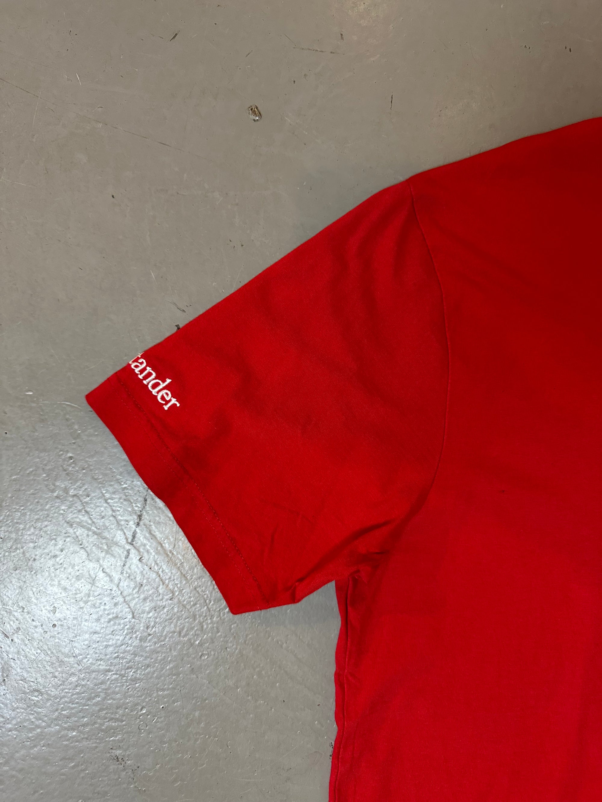 Zu sehnest ein roter Ferrari Tshirt mit dem Logo I der Mitte der Brust 