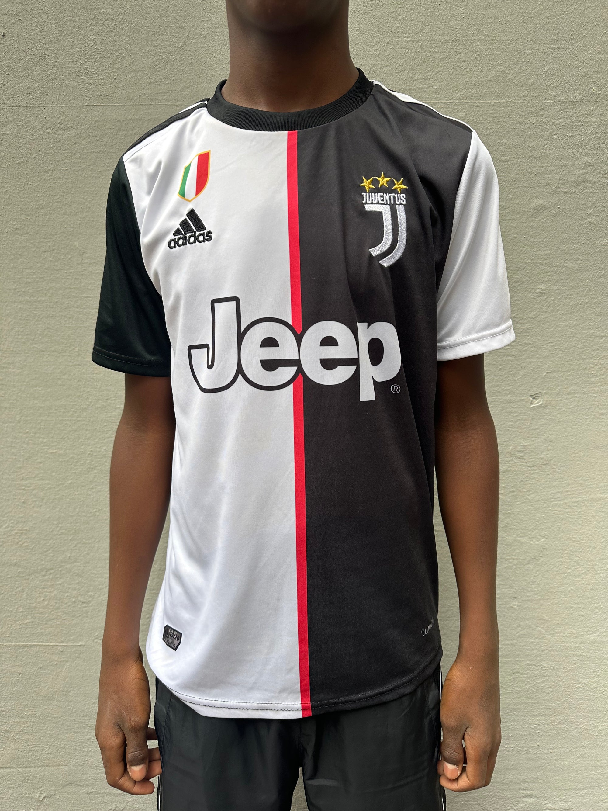 Tragebild Adidas Juventus Trikot vor grauer Wand von vorne.