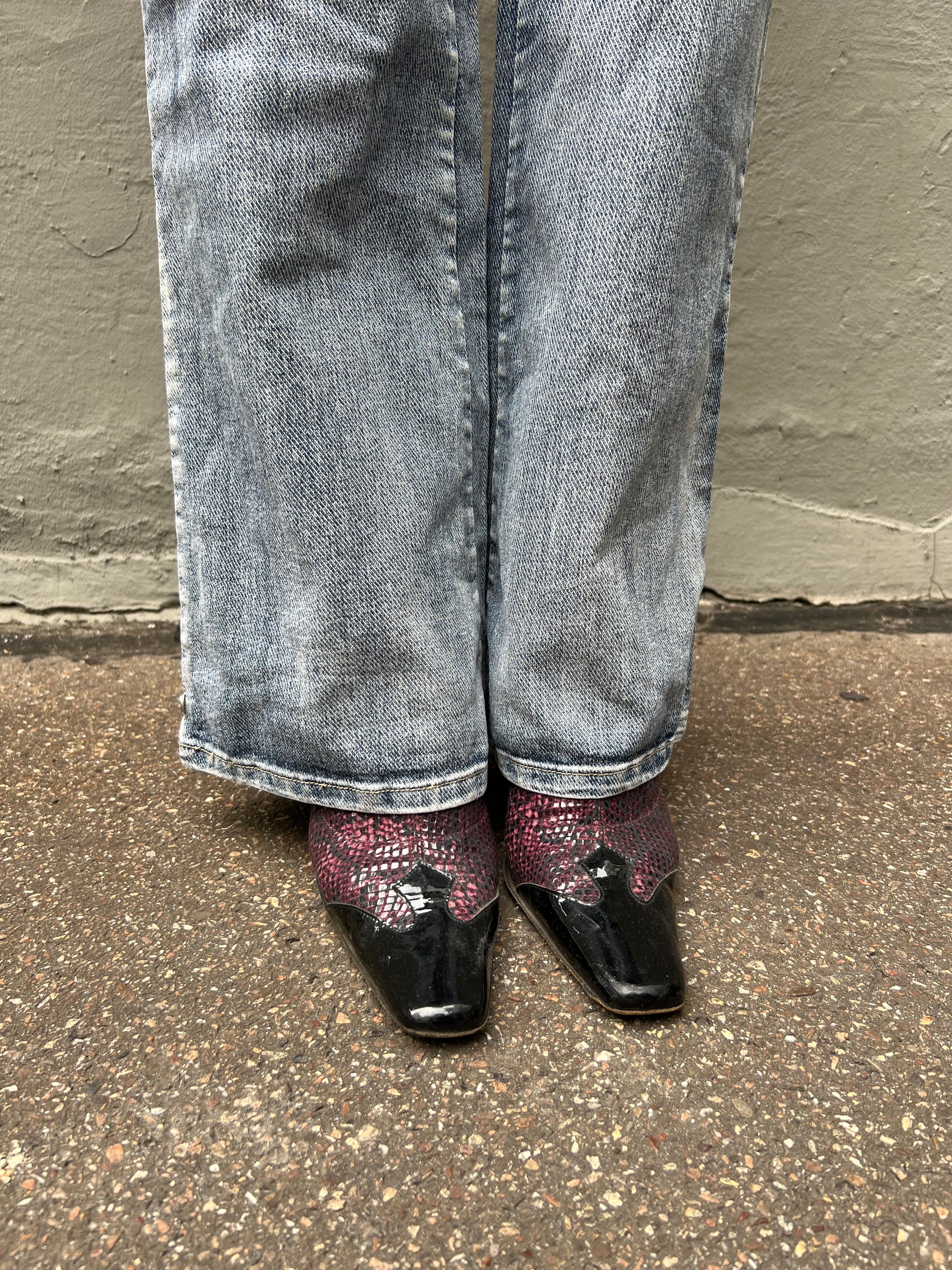 Zu sehen sind lila Vintage Snake Heels getragen vor einem grauen Hintergrund.