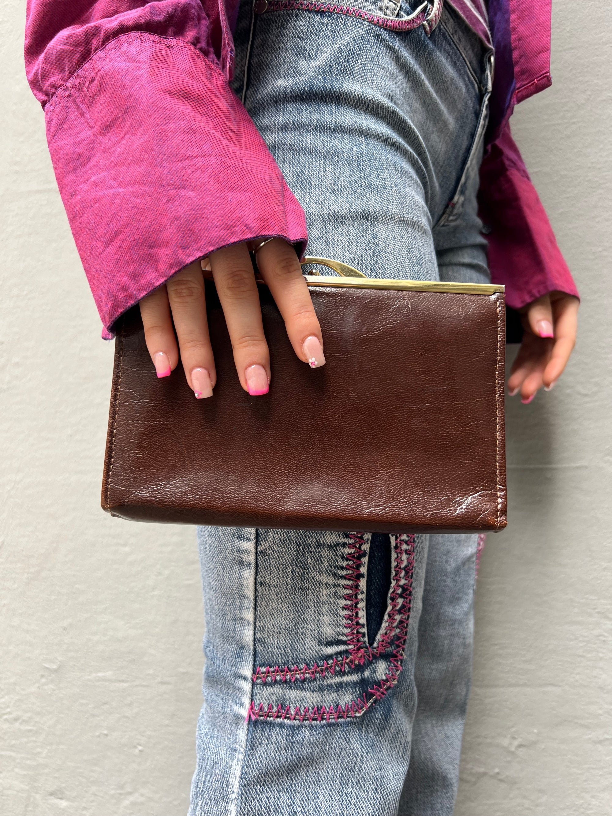 Zu sehen ist eine braune Vintage Leder Tasche getragen vor einem grauen Hintergrund