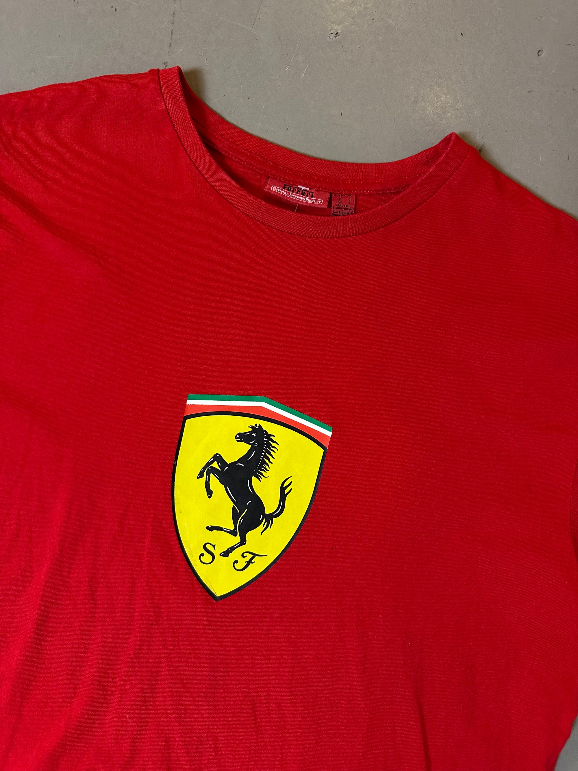 Zu sehnest ein roter Ferrari Tshirt mit dem Logo I der Mitte der Brust 