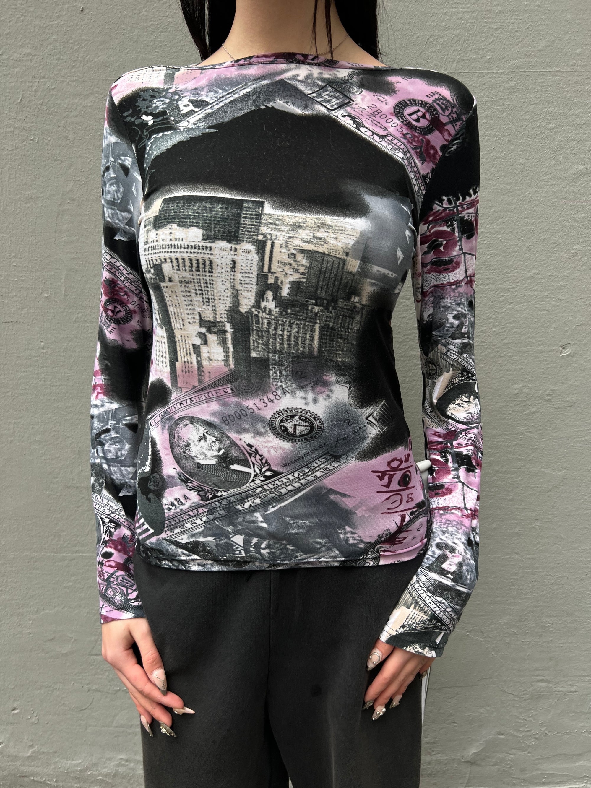 Zu sehen ist ein Longsleeve mit Schwarz Pinken Design mit Wolkenkratzern und Dollar-scheinen in S/M.