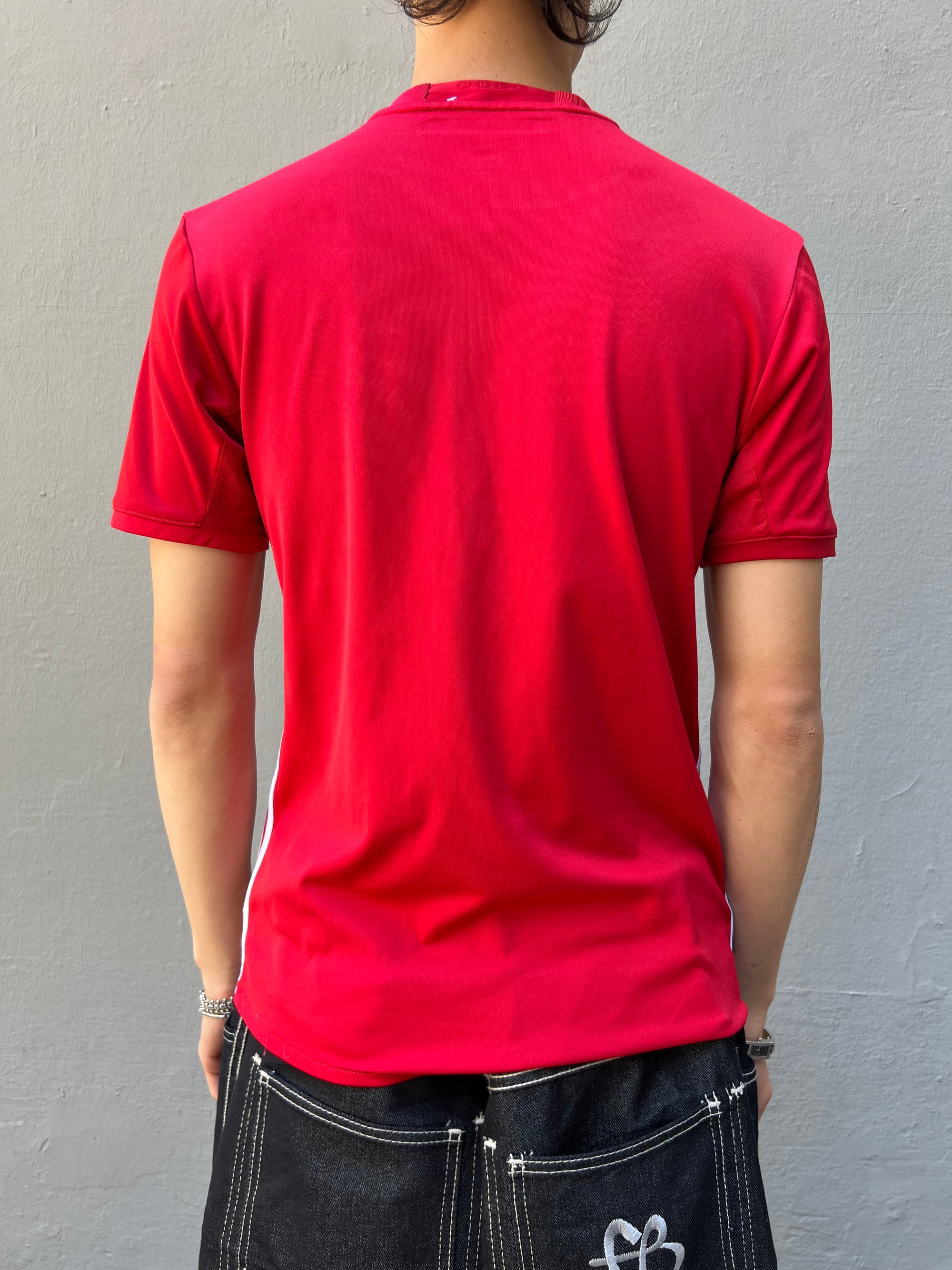 Zu sehen ist ein rotes Vintage Adidas Manchester United Trikot getragen vor einem grauen Hintergrund