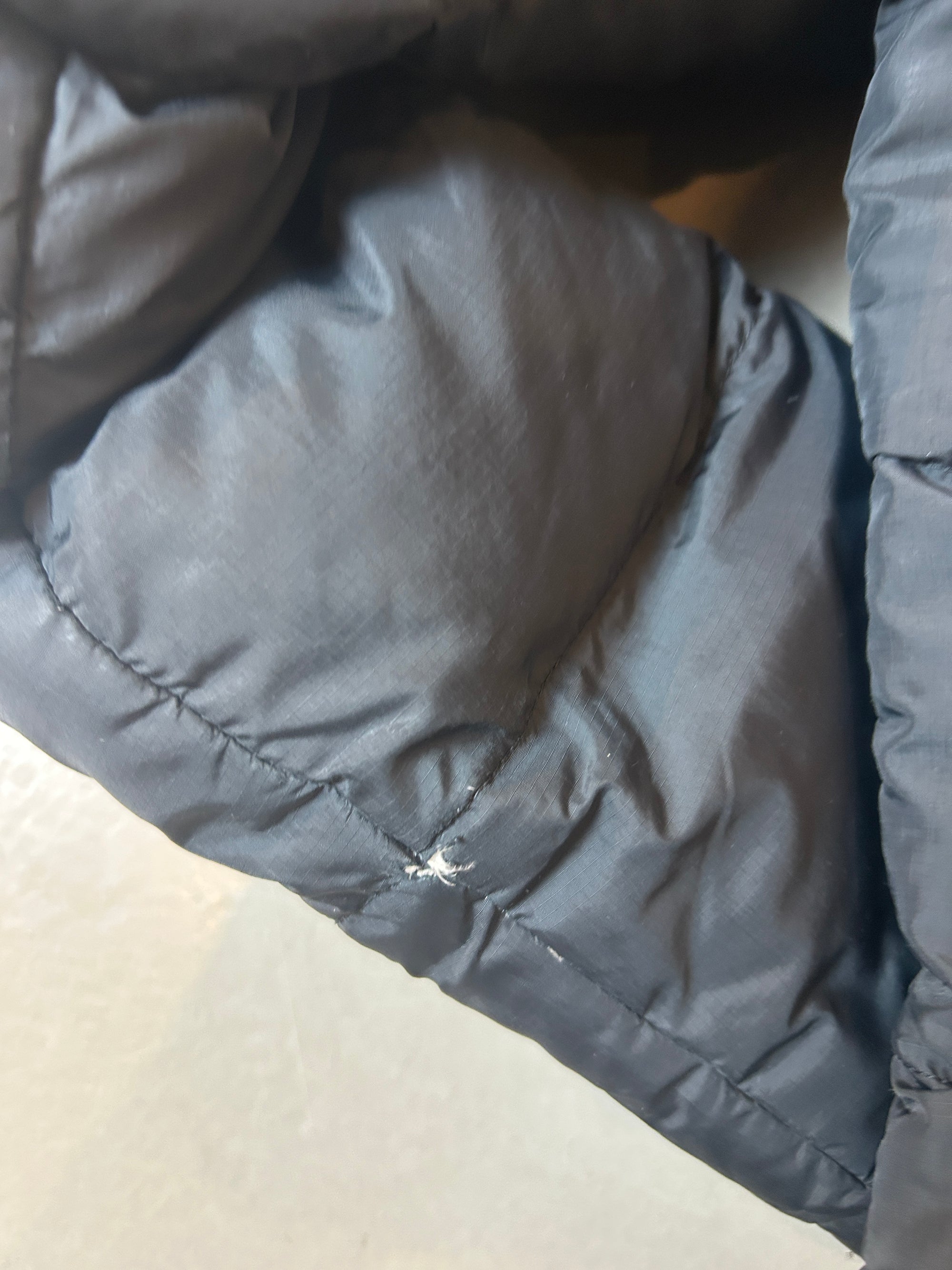 Detailliertes  von Pufferjacke mit Kapuze von vorne auf grauem Boden 